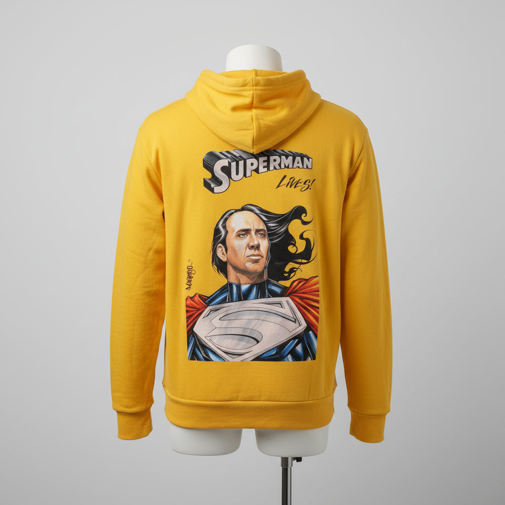 Person wearing a yellow hoodie with a Superman design, standing by a window with a cityscape view.